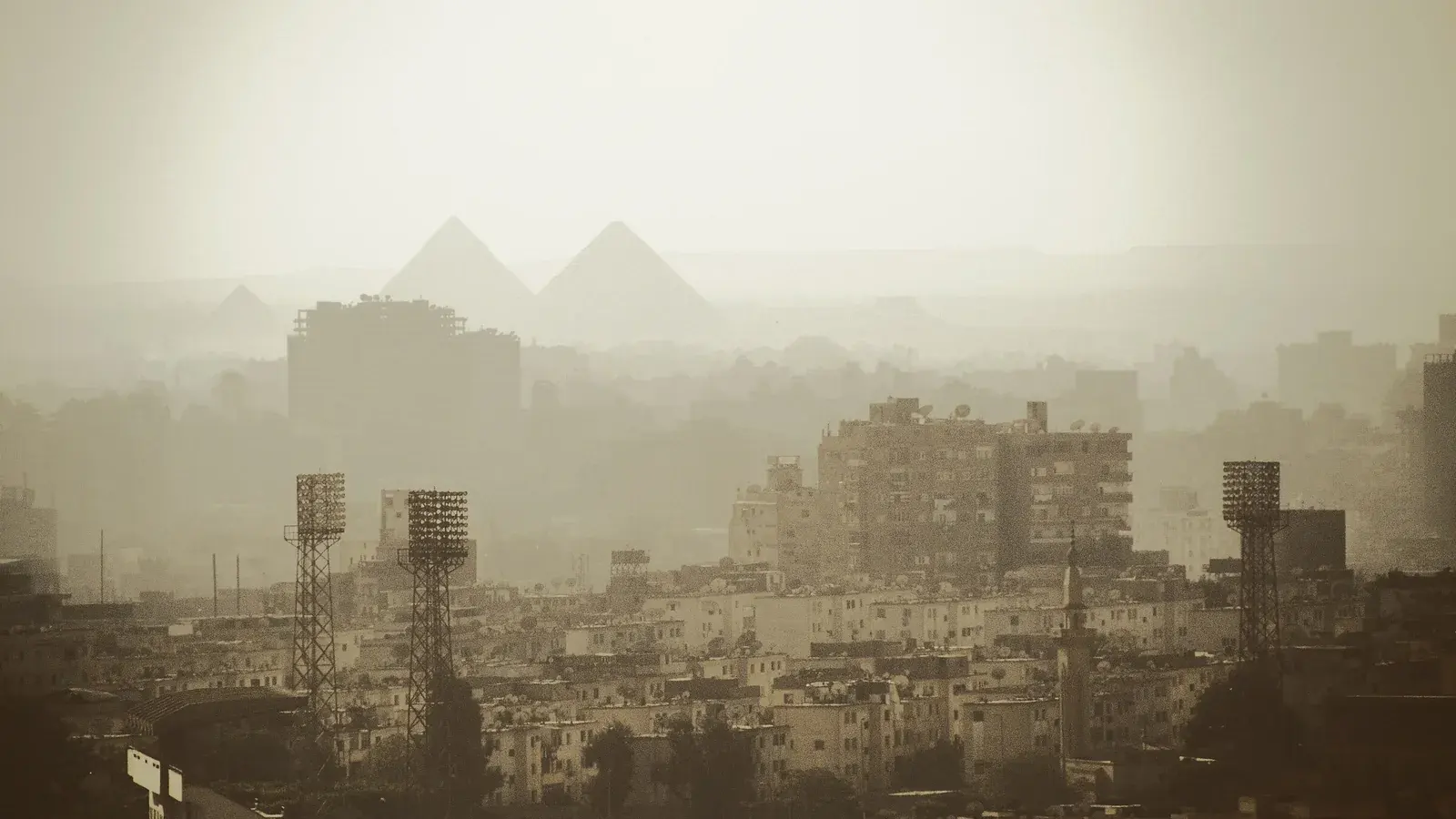 The Giza pyramids on the horizon through haze above the rooftops of Cairo