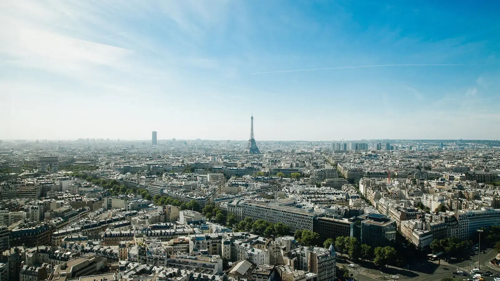 Paris from above on a clear day, the Eiffel Tower and the Arc de Triomphe among the rooftops