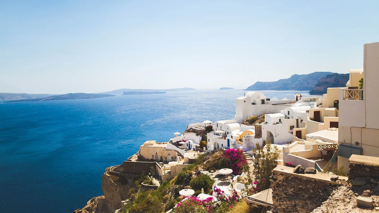 Whitewashed houses stepping down the Santorini caldera rim above a deep blue sea