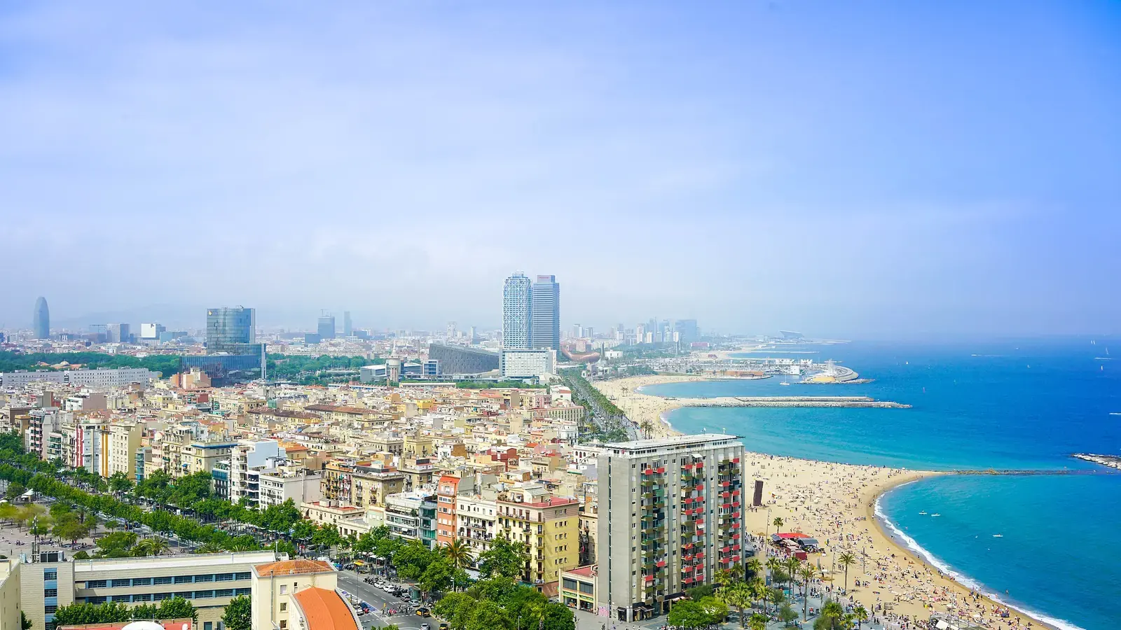 Barcelona from above, the city meeting a curved beach and the blue Mediterranean