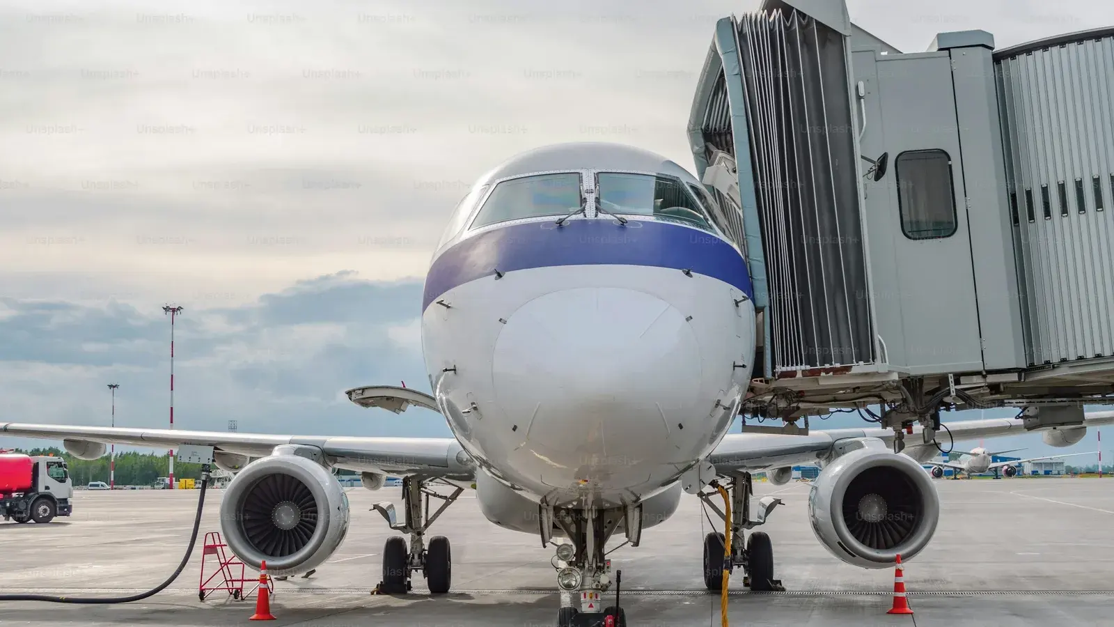 An airliner standing at a boarding bridge on a wet apron, seen from the terminal glass