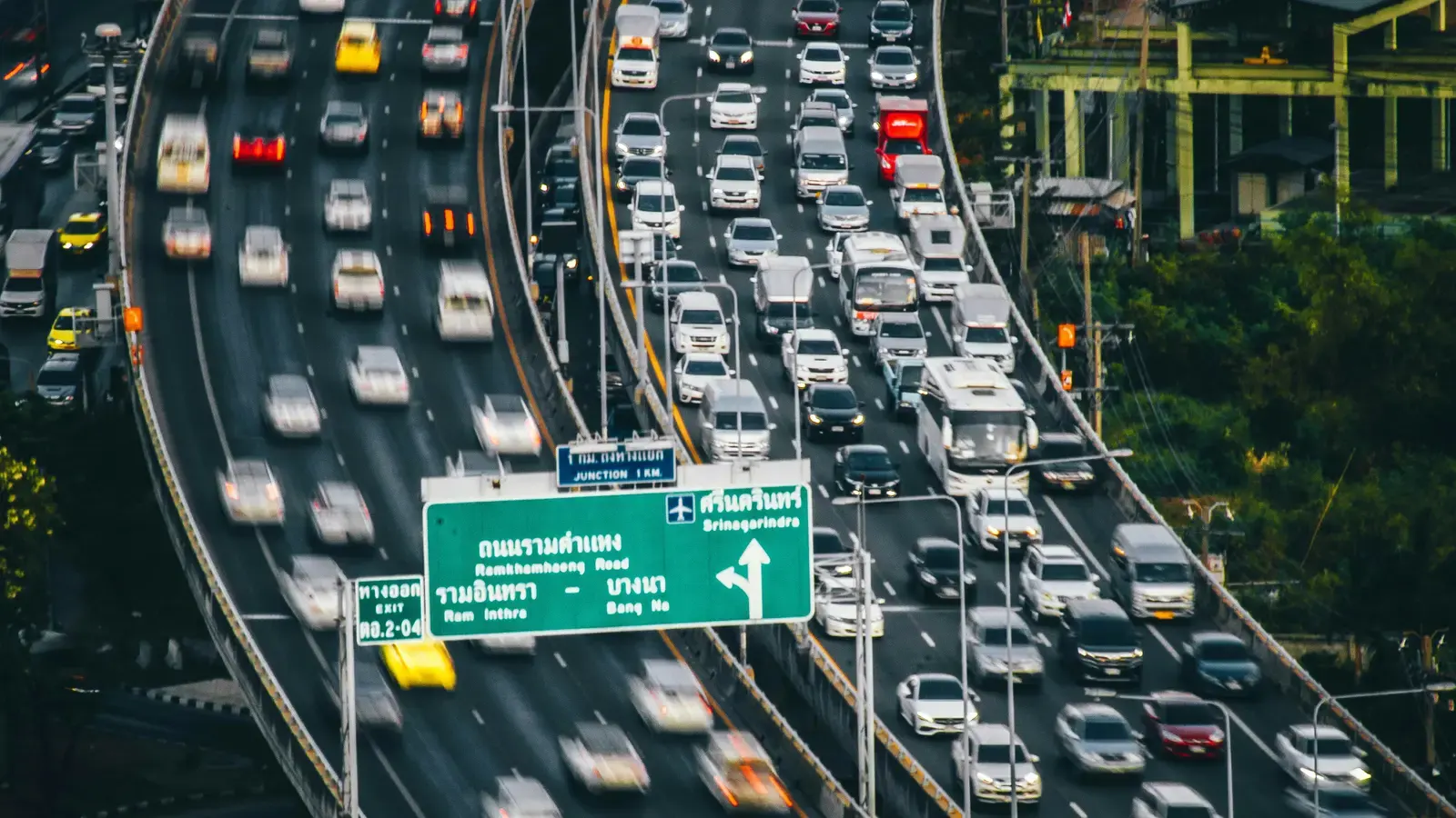 Traffic filling a Bangkok expressway beneath overhead signs in Thai and English