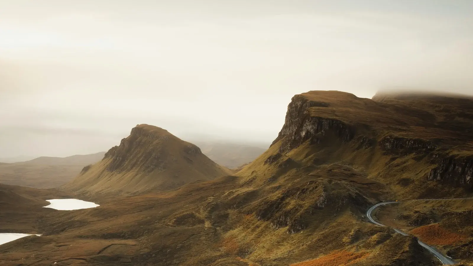 A single-track road winding below the grassy pinnacles of the Quiraing on Skye