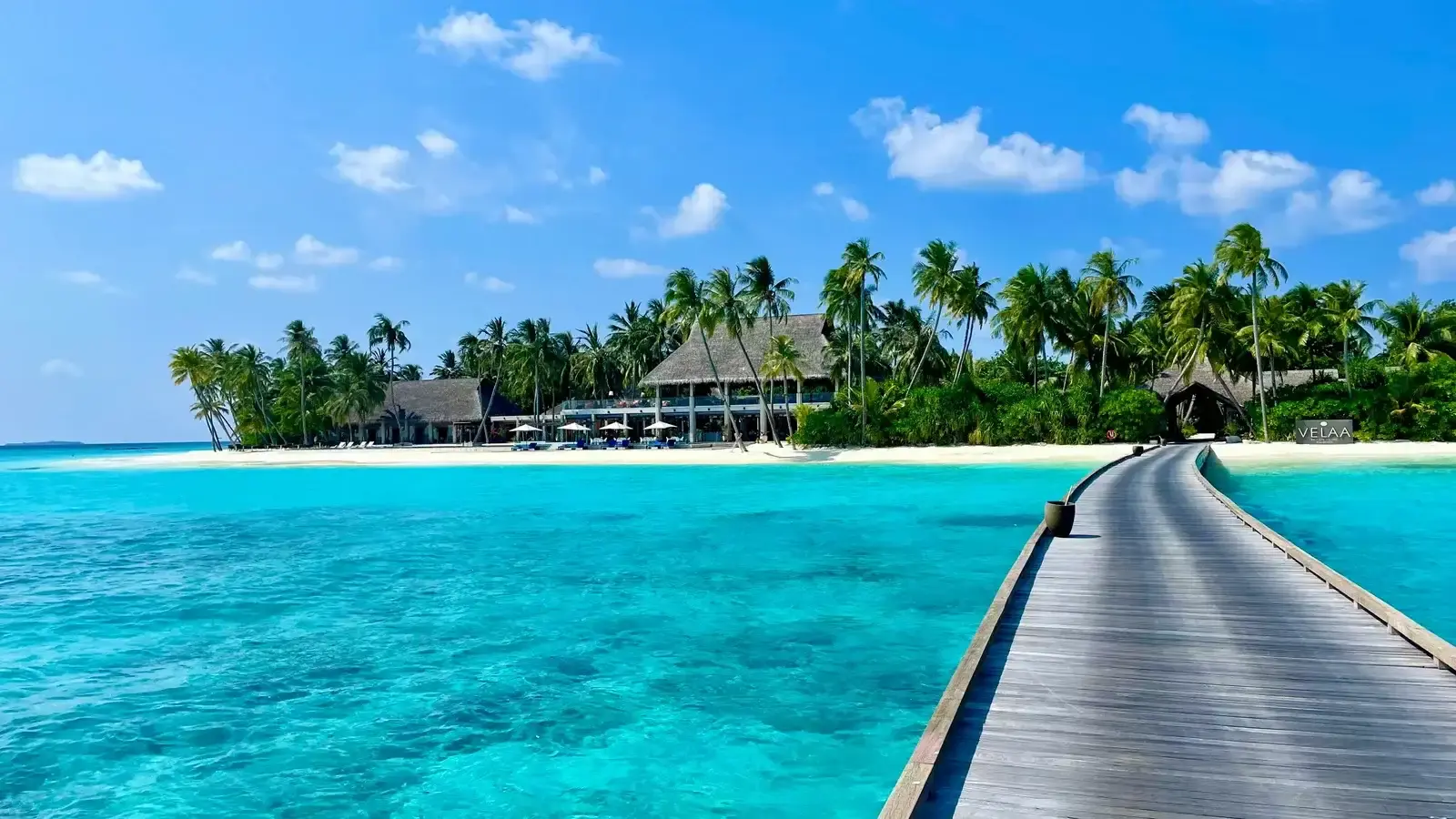 A jetty running out to a resort island's arrival pavilion over shallow water
