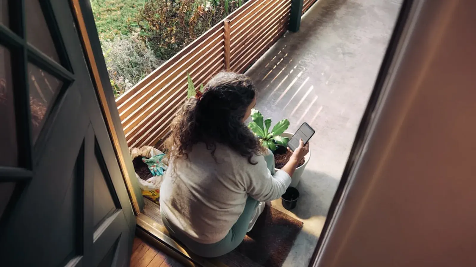 A woman looking at her phone on a porch, seen from directly above
