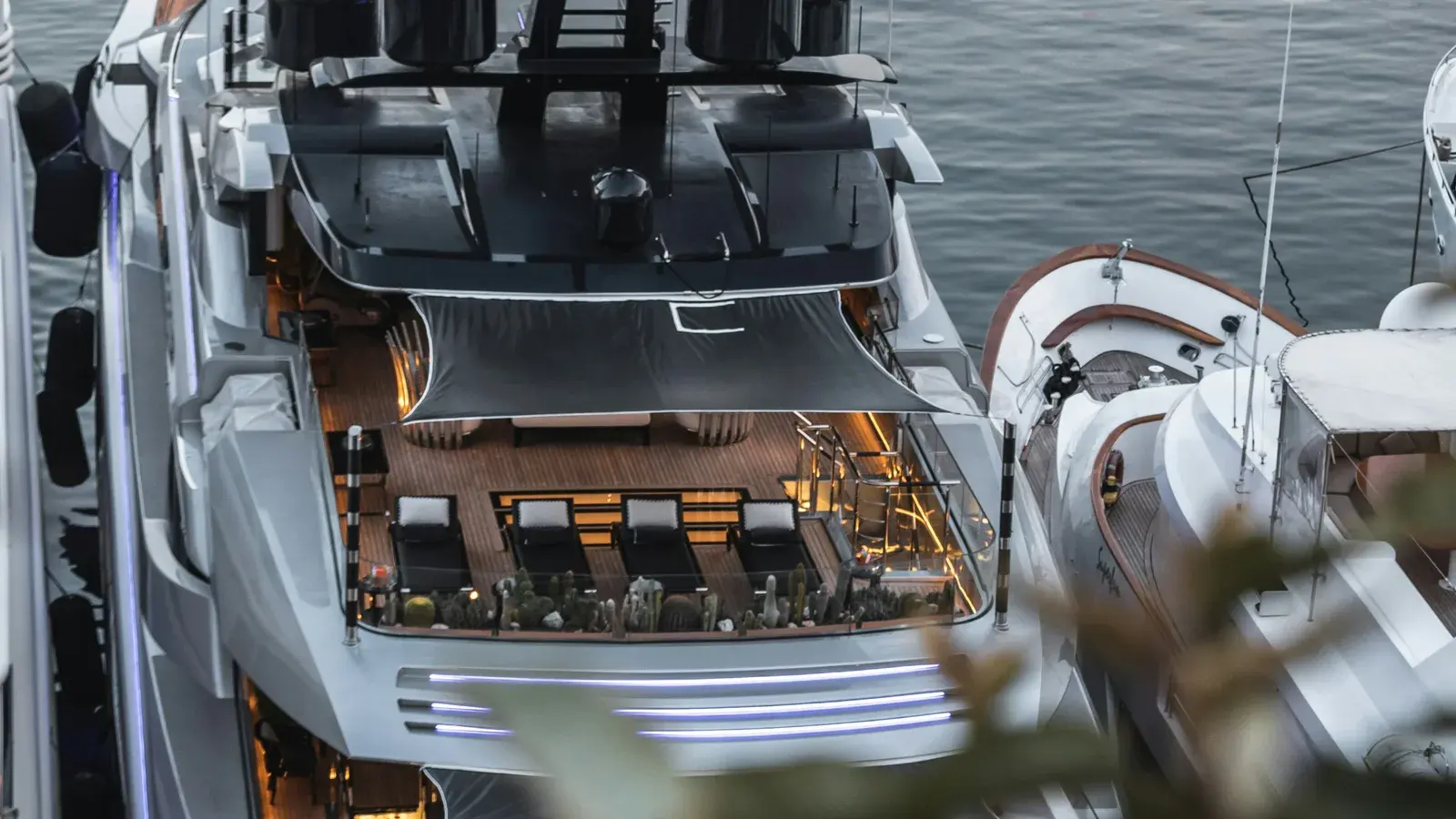 The sun deck of a moored superyacht seen from above, tender alongside
