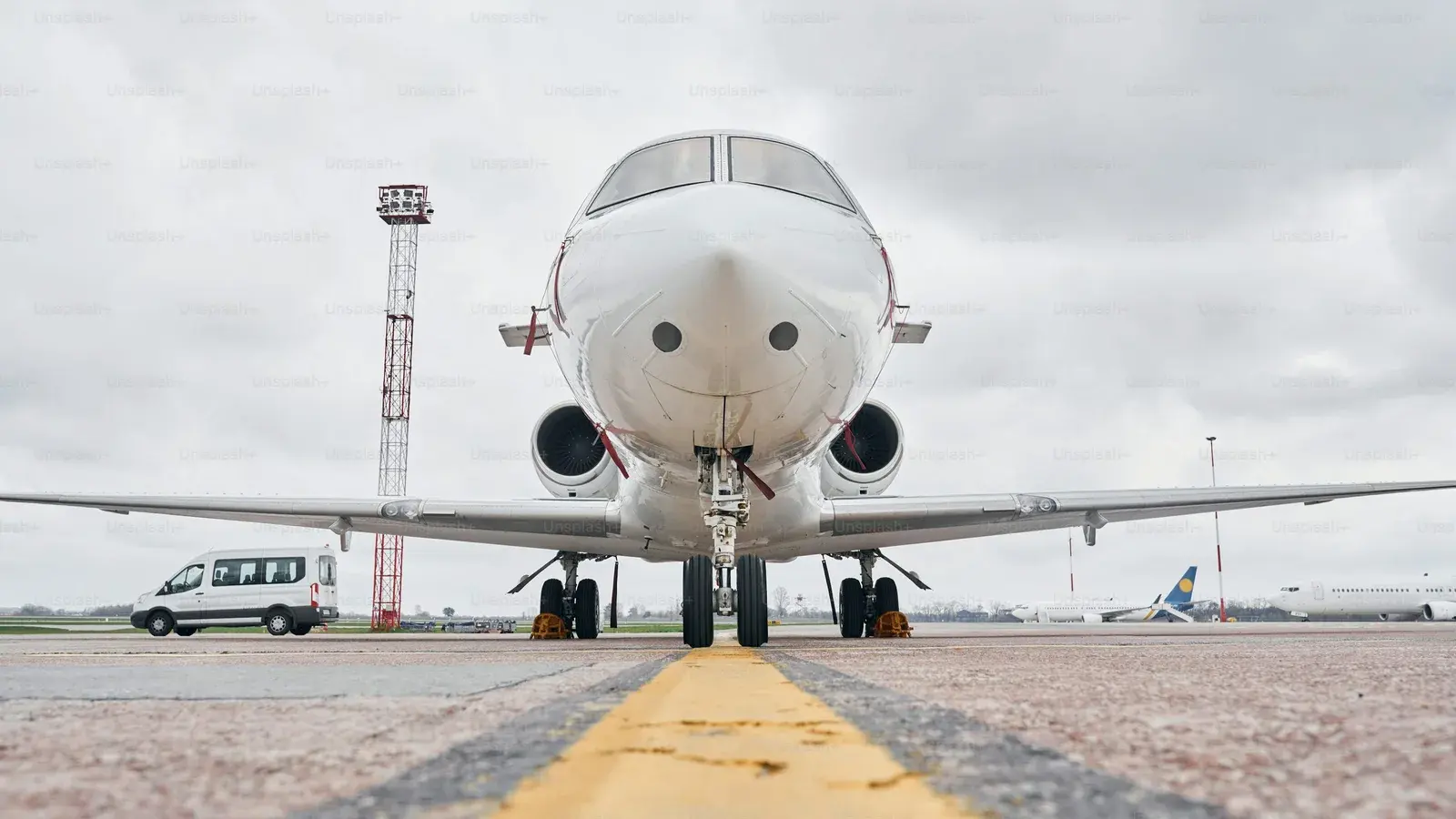 A business jet head-on at an apron, engines and winglets catching the light