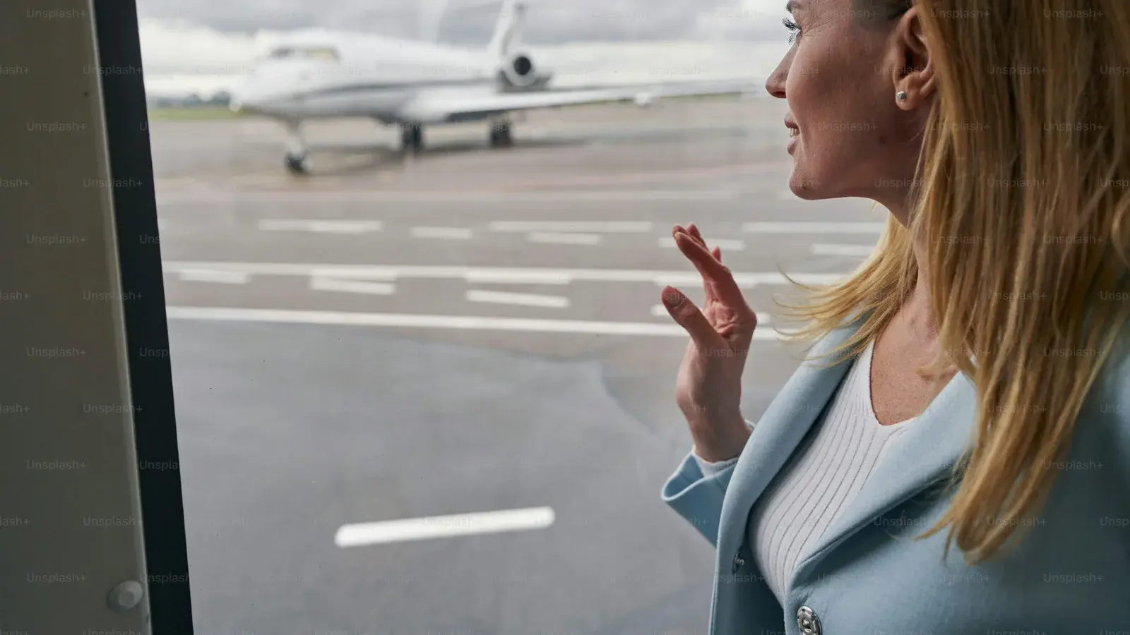 A woman at a terminal window watching a jet on the stand outside
