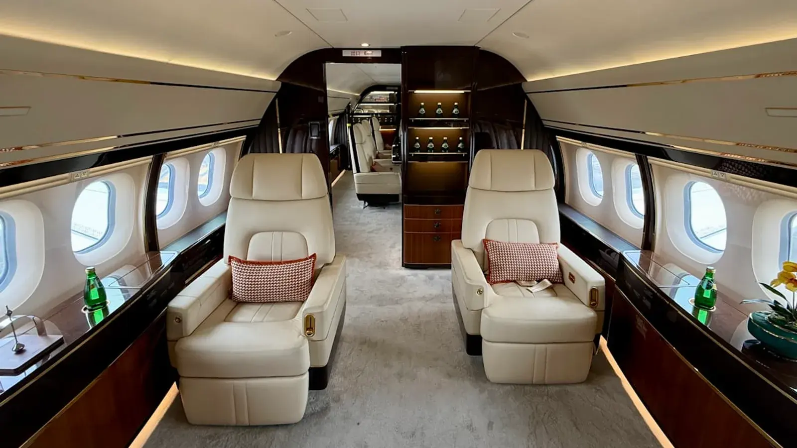 A business jet cabin with cream leather seats and a drinks console