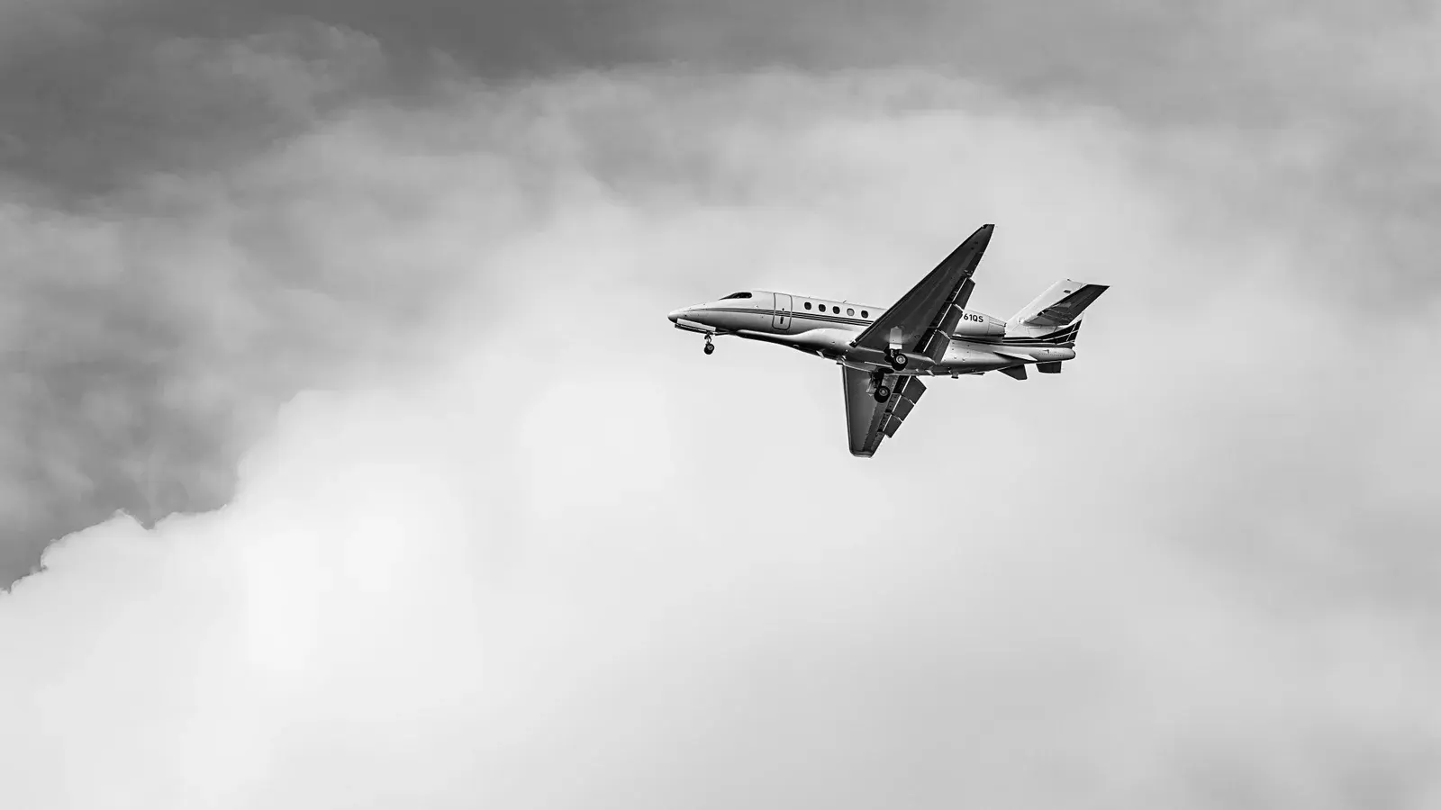 A business jet banking away above a heavy bank of cloud