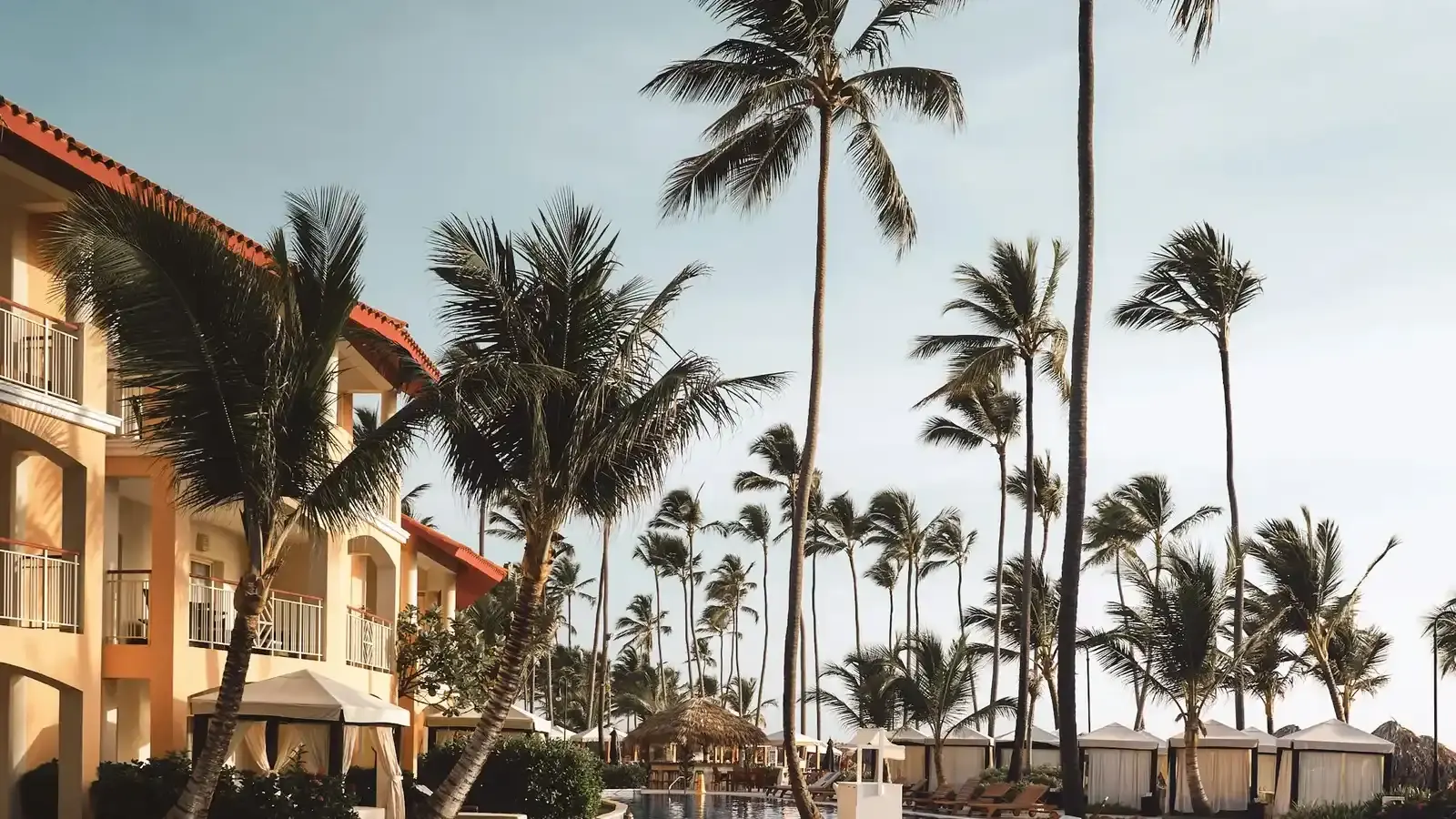 A Caribbean resort building behind palms and shaded cabanas