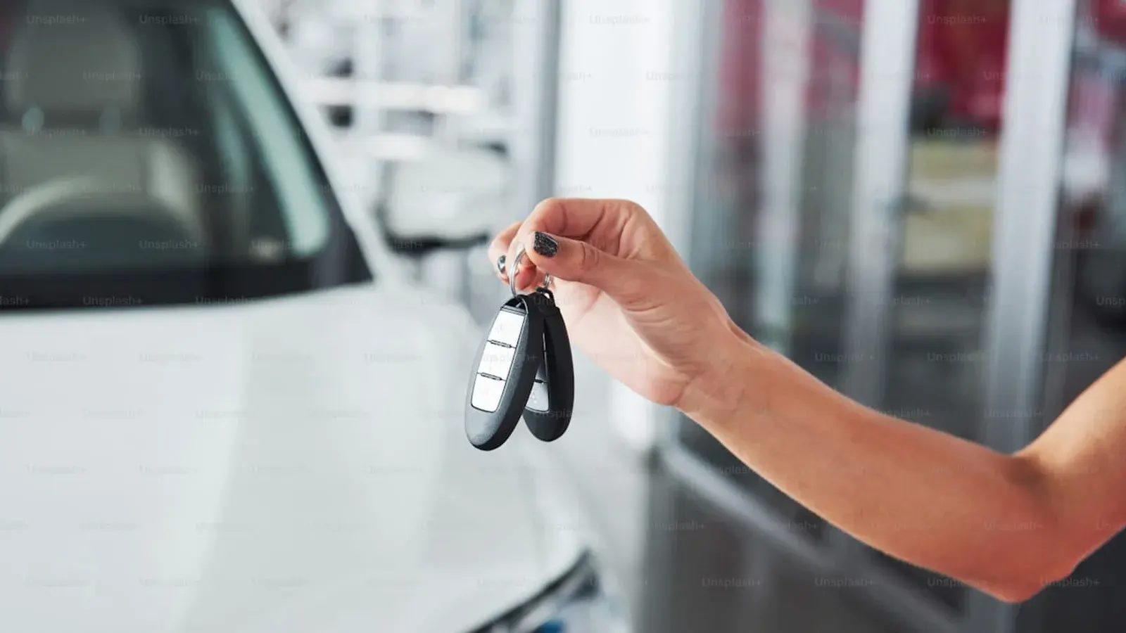 A hand holding a set of car keys above a showroom counter