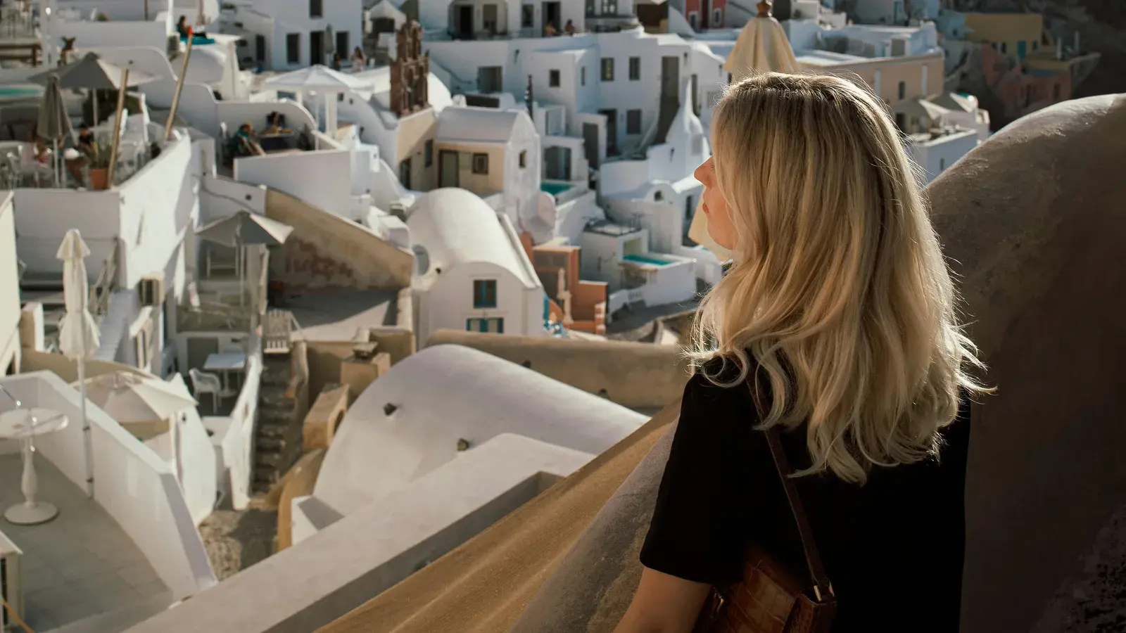 A woman looking out over whitewashed cliffside houses and blue domes