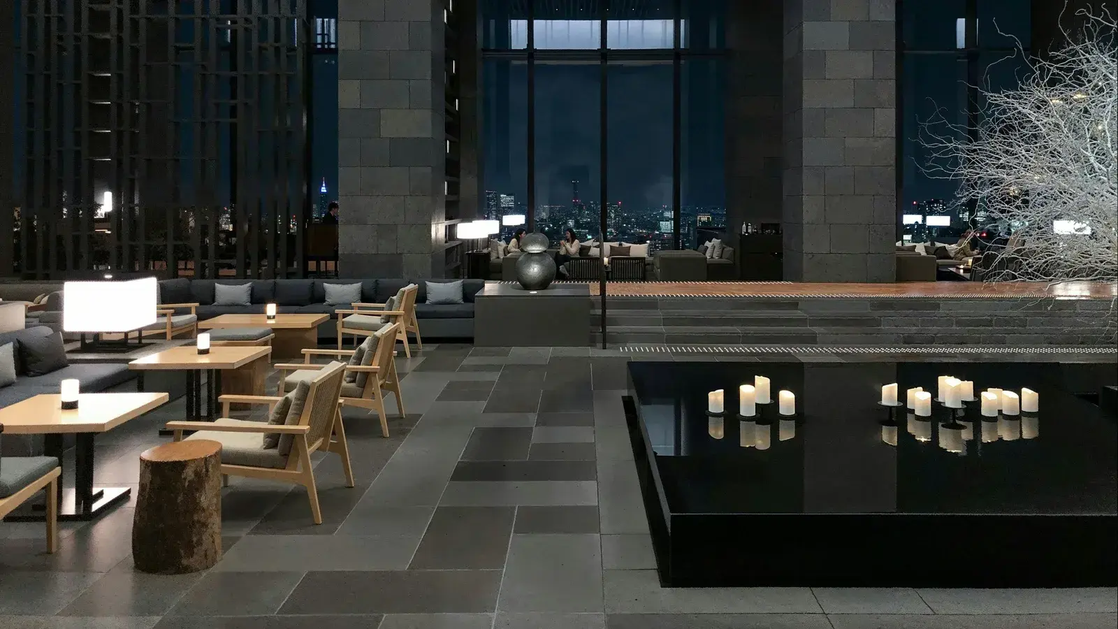 A stone-floored hotel lounge lit by candles, high above a city at night