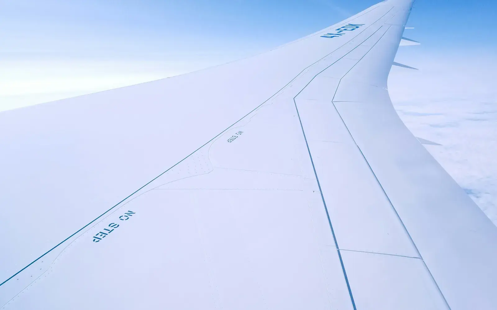 An airliner wing above the cloud layer, seen from a cabin window